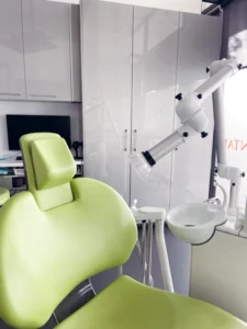 A modern dental office featuring a lime green dental chair and an overhead examination light