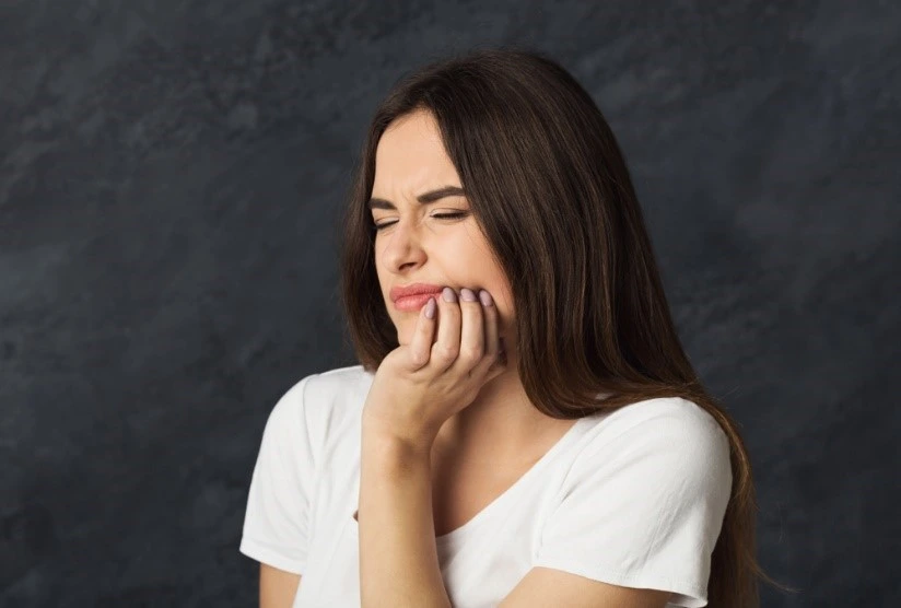 A woman holds her jaw in pain