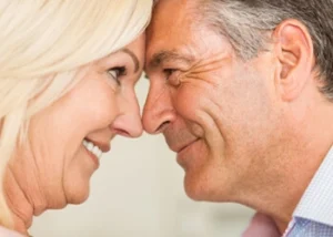 An older couple smiling warmly, heads touching in close-up