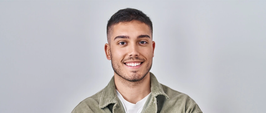 A young man smiles warmly at the camera