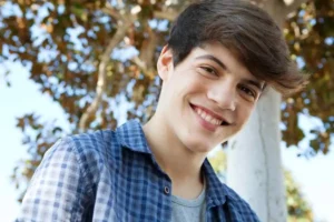 Young person standing in front of a sunlit tree.