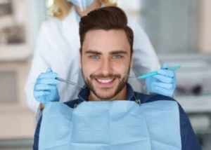 A smiling patient wearing a dental bib during a consultation for veneers for crooked teeth, where a dentist uses specialized tools to demonstrate how porcelain restorations can effectively straighten and align a smile.