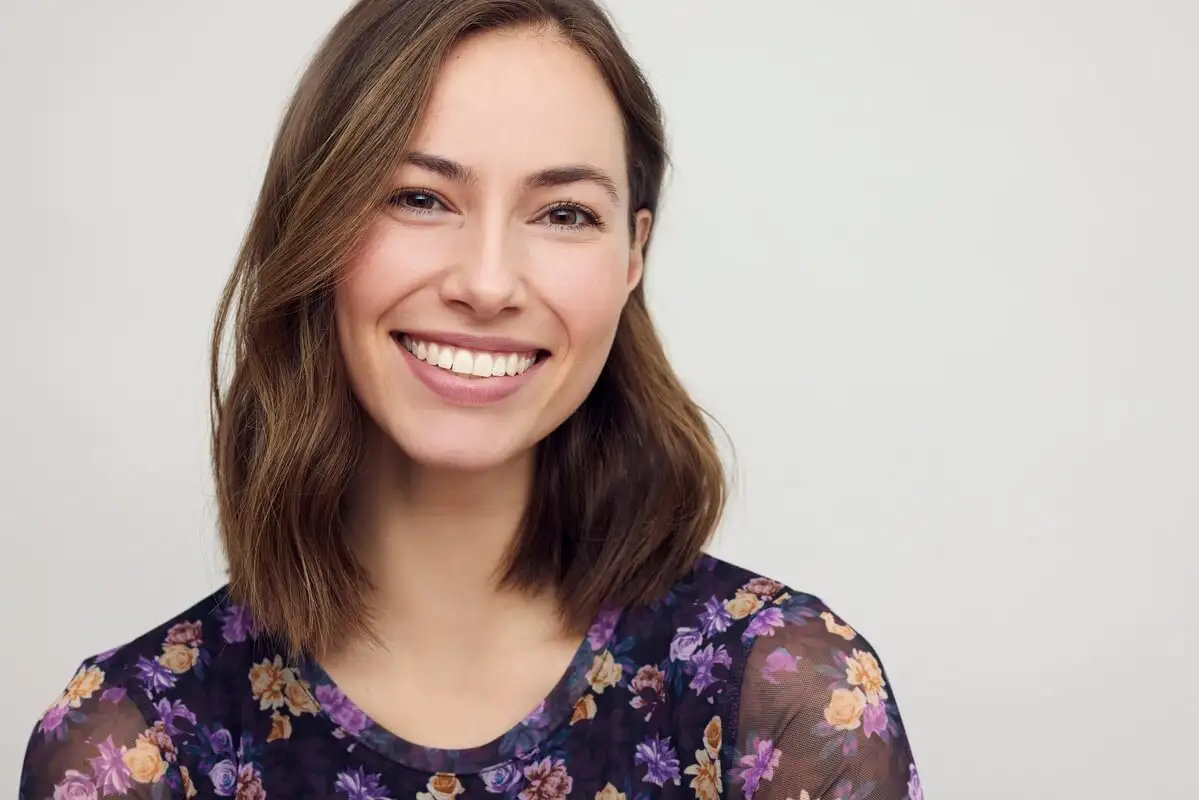 A smiling woman showcasing a radiant, durable smile, representing the long-term value and aesthetic investment of choosing porcelain veneers