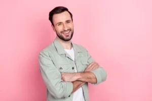 A smiling man with a beard and crossed arms, showcasing a fully restored smile after receiving professional treatment solutions for cracked or damaged teeth.