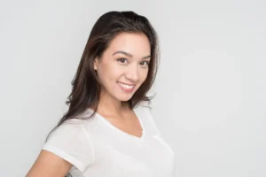 A smiling woman showcasing the natural and symmetrical results of the teeth veneers process, highlighting a bright, confident smile achieved through cosmetic porcelain veneers.