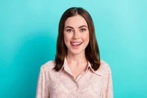 A woman in a floral shirt playfully sticking out her tongue, showcasing a healthy tongue and bright smile to highlight the importance of complete oral hygiene and fresh breath