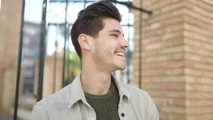 A smiling man showing off the natural brilliance of his smile in outdoor lighting, highlighting the realistic appearance and durability found in the comparison of composite vs porcelain veneers.