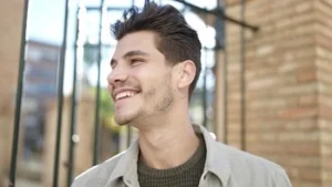 A smiling person showcasing the natural aesthetics of their smile in sunlight, representing the key factors in choosing veneer materials for teeth that look realistic in any environment.