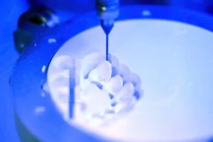A CNC machine precisely milling a dental prosthetic from a white block under blue light, conveying high-tech precision and innovation.