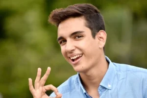A smiling young man making an 'OK' hand gesture, symbolizing the successful relief of a toothache and the comfort of returning to a pain-free life after dental treatment