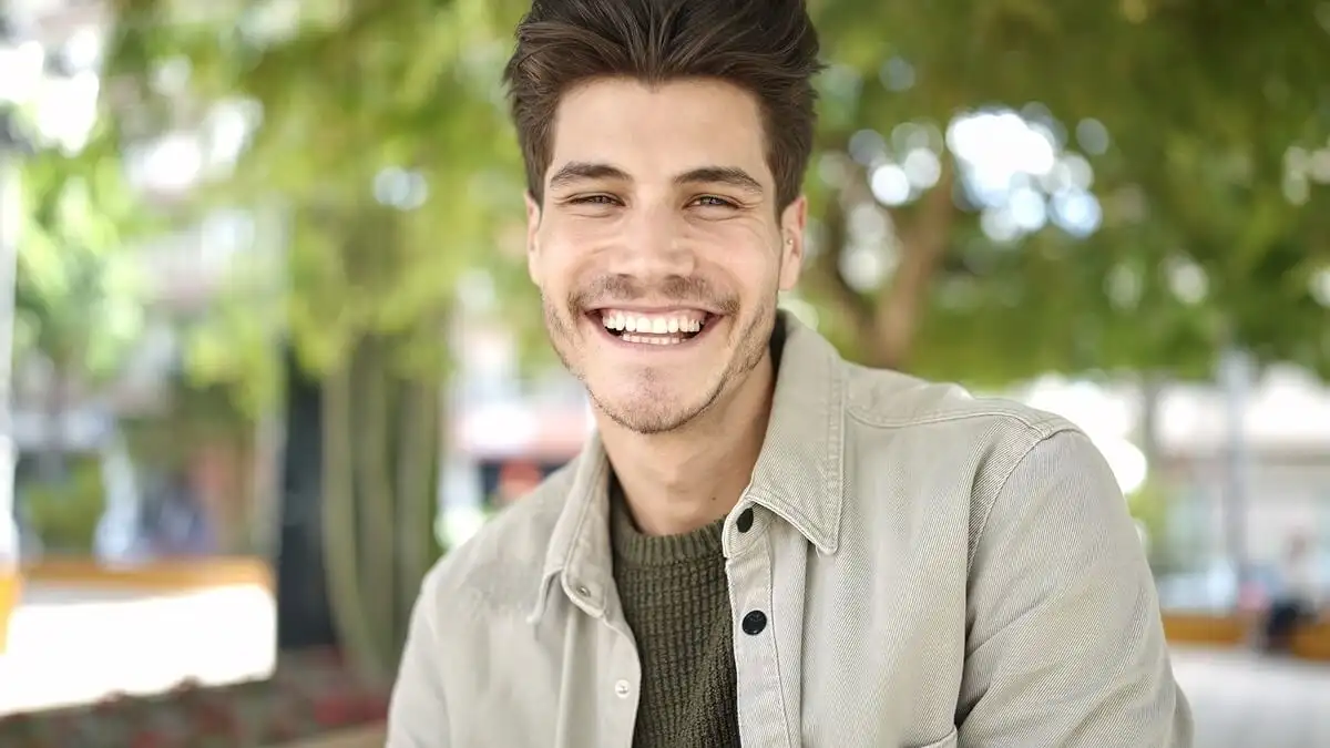 A person showcasing a radiant, natural-looking smile in outdoor lighting, providing a real-world example of how veneers work to transform aesthetics while maintaining a joyful and authentic appearance.