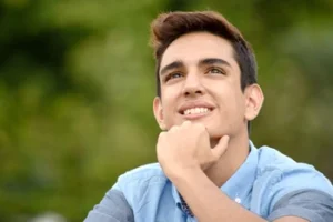 A young man looking upward with a thoughtful expression, contemplating his options for toothache relief and deciding on a professional dental solution to restore his oral health