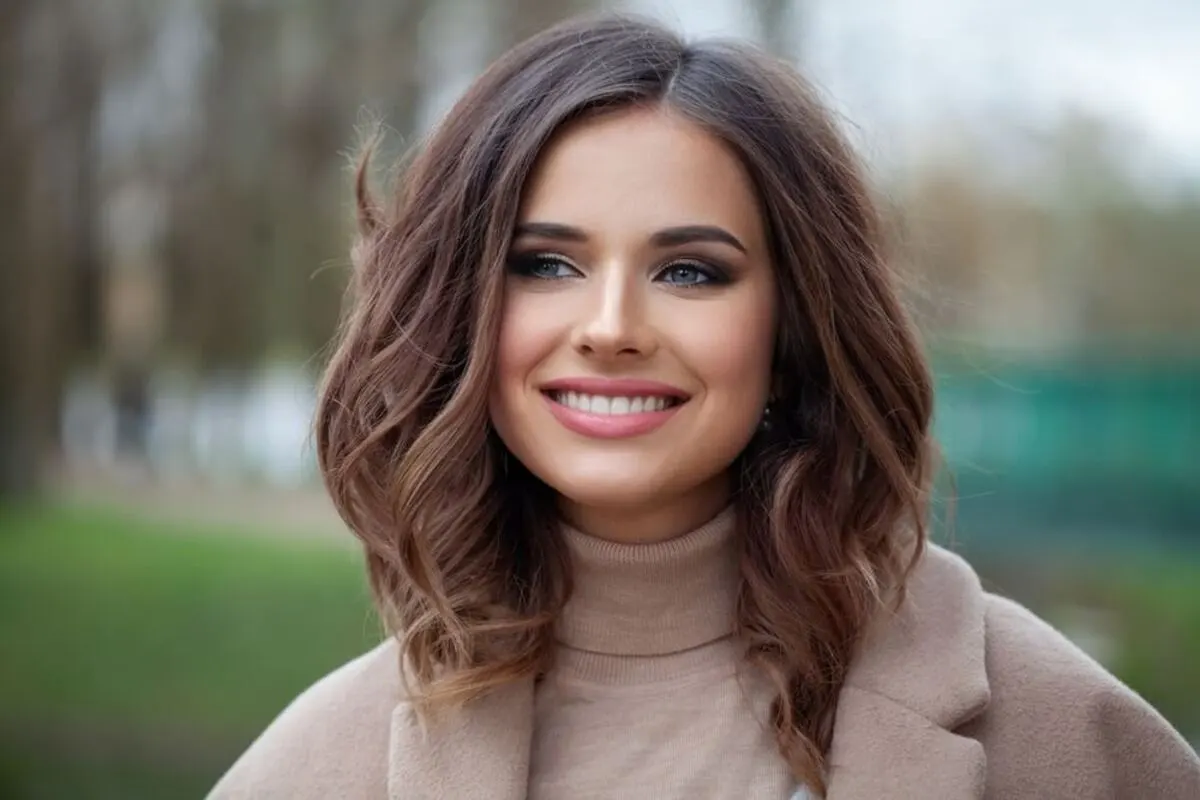 A woman smiling warmly to showcase a bright, healthy, and natural-looking smile, representing the aesthetic benefits of professional dental care