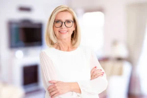 A smiling woman wearing glasses and a professional white blouse with arms crossed, reflecting the approachable and expert nature of the Finesse Dental team