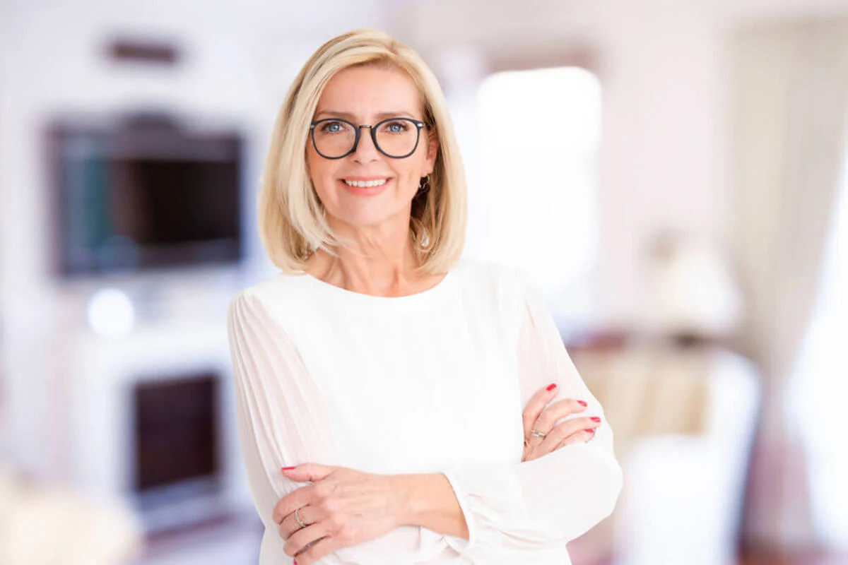 A smiling woman wearing glasses and a professional white blouse with arms crossed, reflecting the approachable and expert nature of the Finesse Dental team