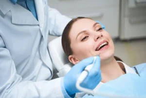 sinus tooth pain check A woman in a dental chair smiles while a dentist, wearing gloves, holds a dental tool near her mouth