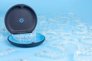 Invisible,Retainers,Case,With,Orthodontic,Aligner,Brackets,Thrown,Around.,Black Open dental aligner case with a clear aligner inside