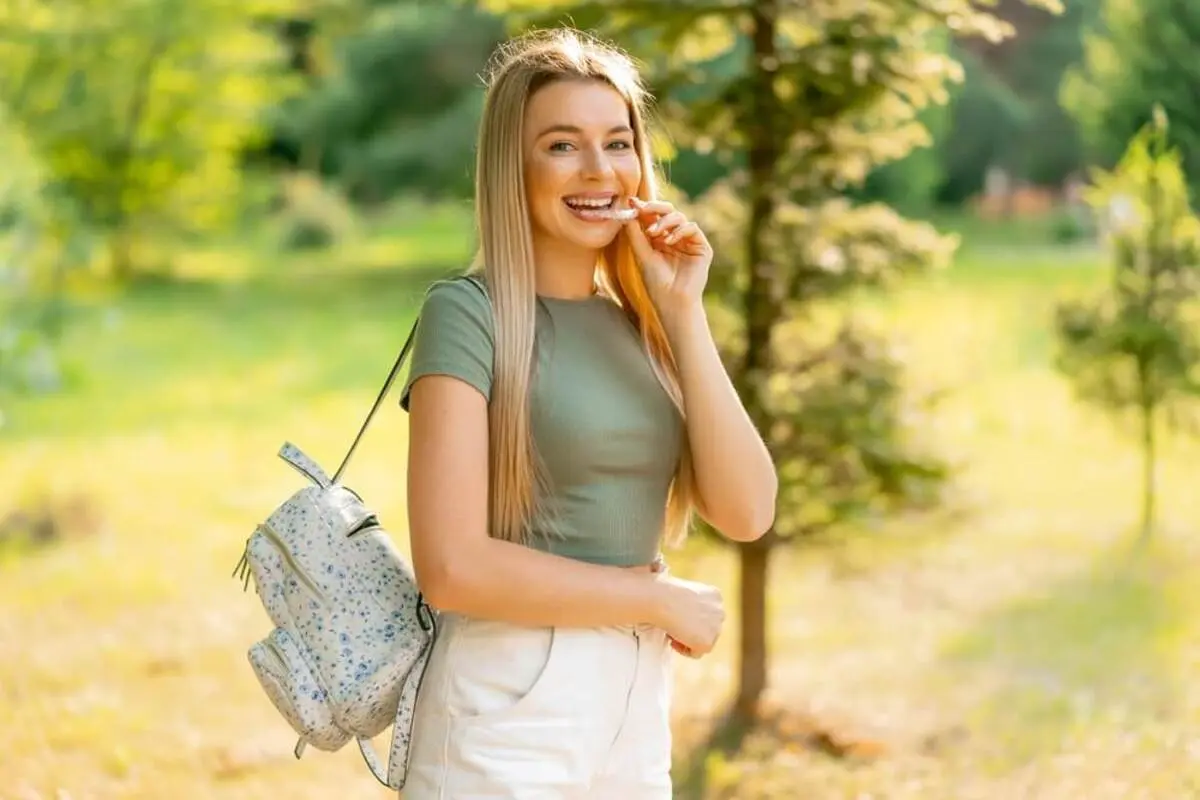 A young patient holding her clear aligner, showcasing a healthy smile