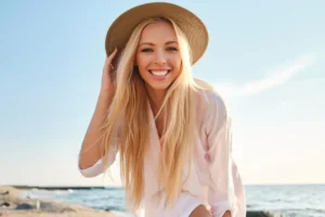Young woman with a healthy smile posing at the beach against ocean waves
