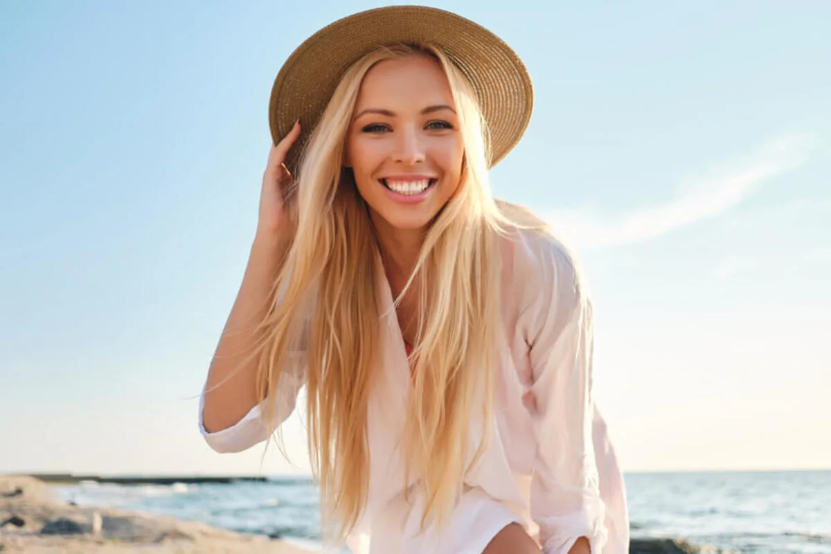 Young woman with a healthy smile posing at the beach against ocean waves