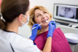 Dental Implant Thailand checkup A dentist wearing gloves and a mask examines a smiling woman in a dental chair