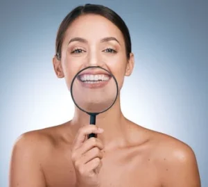 Tooth Cavity Pain check A smiling woman holds a magnifying glass in front of her mouth, enlarging her smile