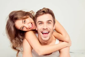 Confident and healthy smiles a joyful woman hugging her partner from behind, showcasing radiant dental health