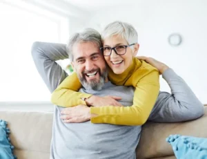 A happy older couple embraces on a beige sofa
