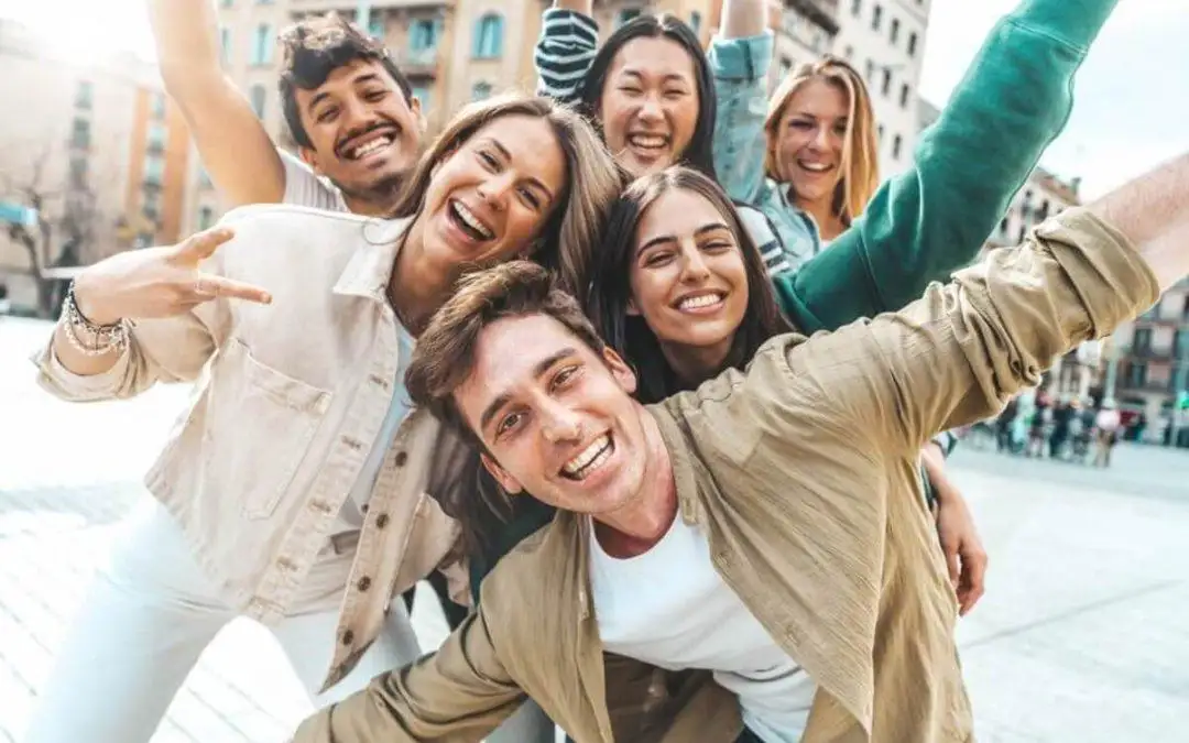 Six cheerful friends posing outdoors and showcasing their healthy, confident smiles