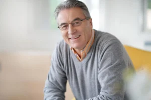Smiling senior man in a bright room displaying a healthy, clear smile after dental treatment