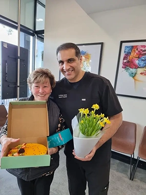 A women holds a cake together with Dr Sehmi