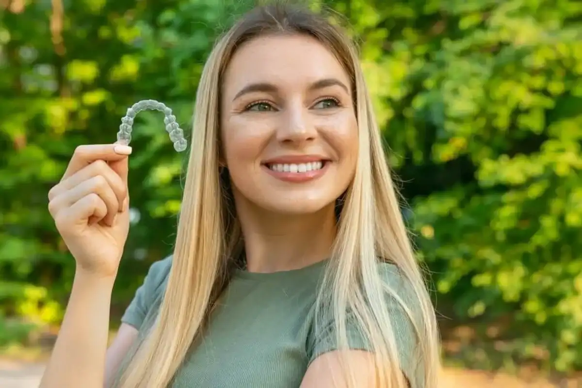 Patient showcasing her Invisalign clear aligner in natural light