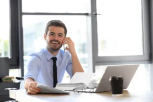 A man smiles warmly at a desk, satisfied with the results after a dental filling for his tooth sensitivity