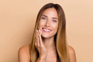 A woman touches her cheek and points to the area where she is experiencing wisdom tooth pain