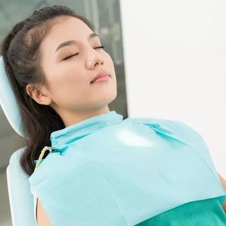 A woman resting comfortably in a dental chair while undergoing IV sedation sleep dentistry, appearing completely relaxed and peaceful during her stress-free dental procedure.