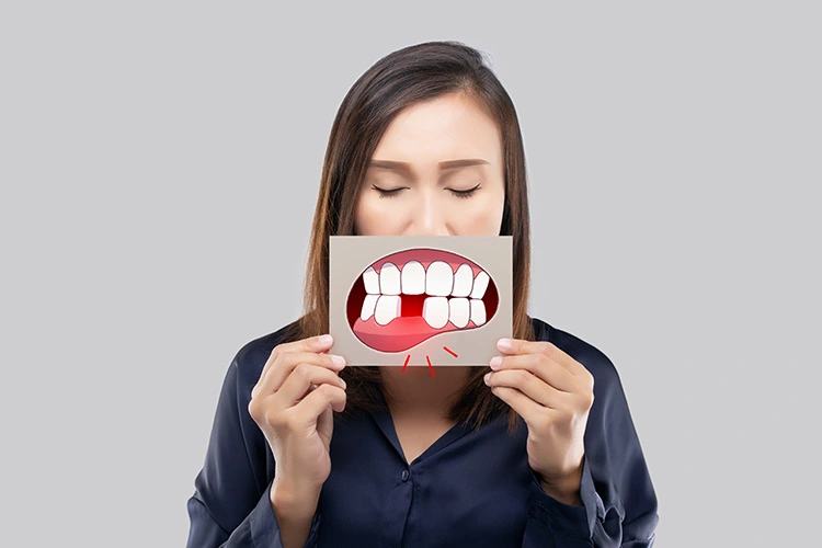 A woman holds a card with an illustration of a painful toothache in front of her mouth