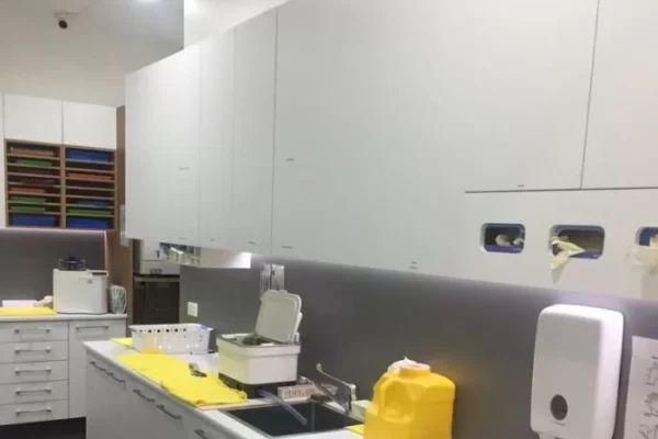 A clean, modern dental clinic setup with white cabinetry, sterilization equipment