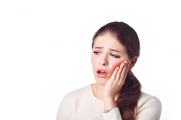 A woman holds her cheek with a pained expression, conveying discomfort