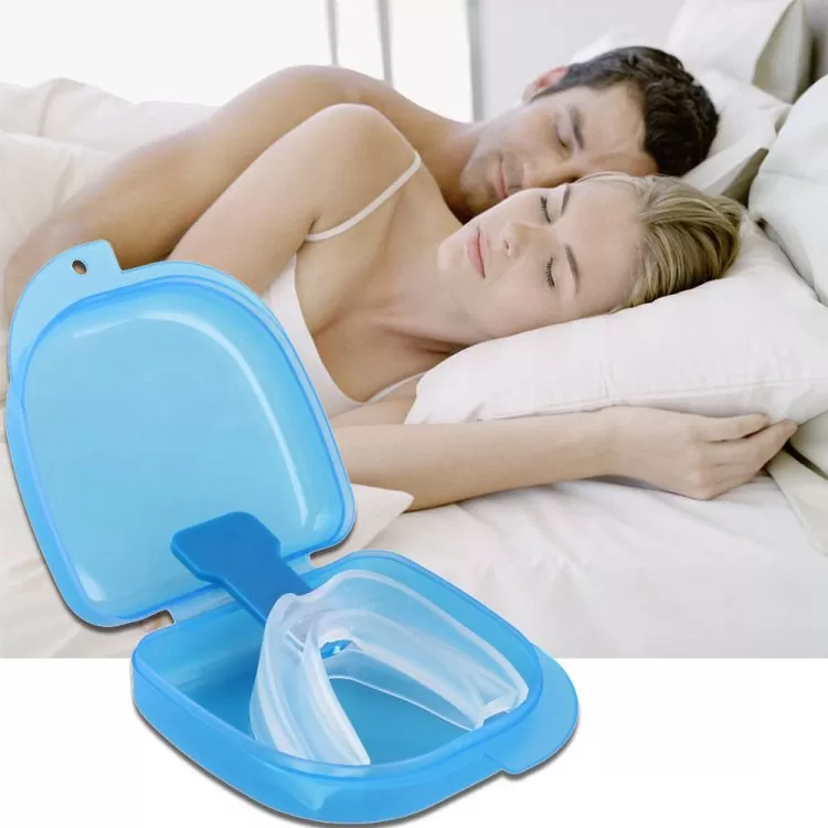 A couple sleeping in bed. In the foreground is a case displaying a white mouthguard