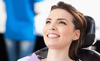 A women smiles while sitting in a dentist's chair