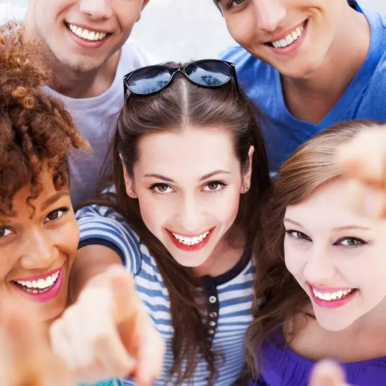 A group of five friends, diverse and cheerful, smile brightly at the camera.