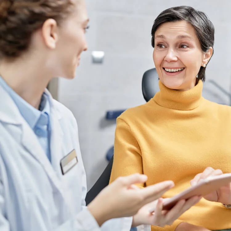 Cheerful woman talks to a healthcare professional. Both are smiling, suggesting a positive, warm interaction