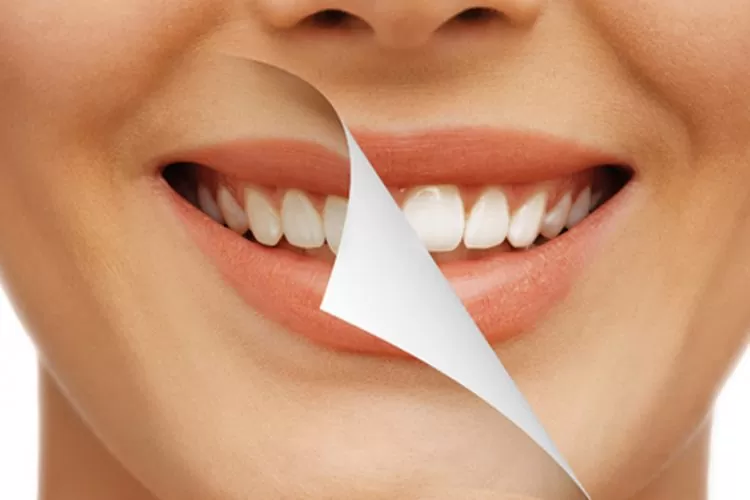 Smiling face with peeled section revealing whiter teeth beneath, symbolizing teeth whitening. Emphasizes contrast and improvement in dental appearance.