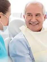 An older male patient conversing with medical staff during a consultation