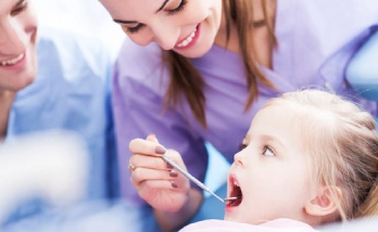 A dentist examines a young girl's teeth using a dental mirror